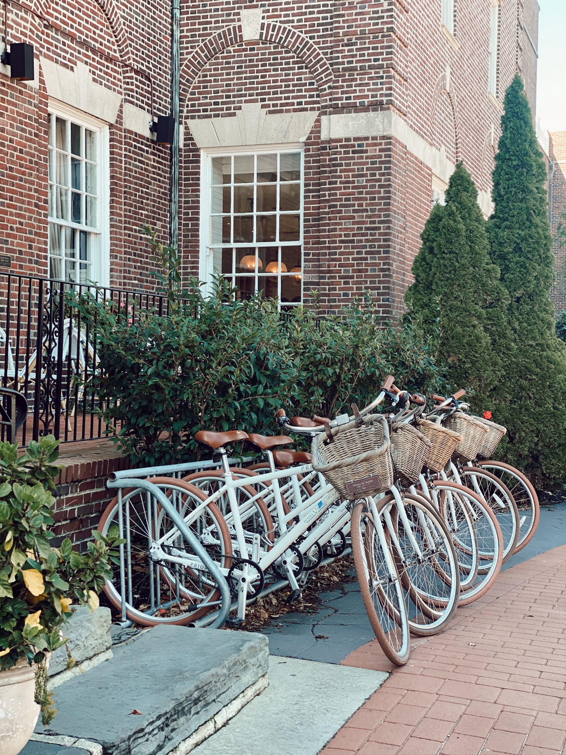 white bicycles lined up in front of a brick hotel 